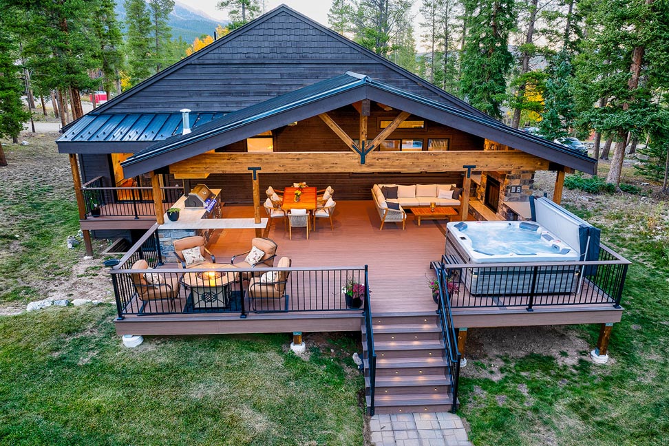Outdoor living with a deck cover, hot tub, outdoor kitchen, and lounge area. 